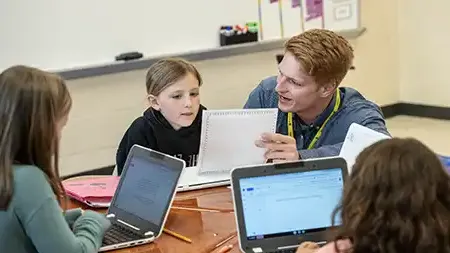 Male teacher educating a small group of children.